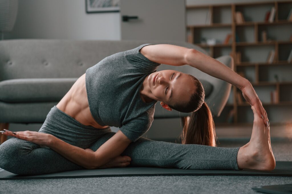 Stretching the spine. Young woman in yoga clothes doing fitness indoors